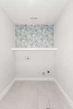 Laundry area with hookup for an electric dryer, gas dryer hookup, washer hookup, and tile patterned flooring