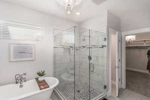 Bathroom featuring tile patterned flooring, separate shower and tub, and a notable chandelier