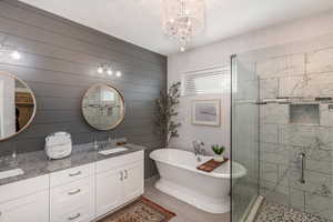 Bathroom featuring tile patterned flooring, dual bowl vanity, independent shower and bath, wood walls, and a notable chandelier