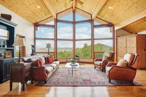 Living room with beam ceiling, light hardwood / wood-style flooring, and wooden ceiling