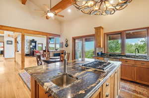 Kitchen featuring light hardwood / wood-style floors, beamed ceiling, sink, and an island with sink