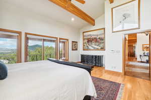 Bedroom featuring light hardwood / wood-style floors, beamed ceiling, access to outside, and high vaulted ceiling