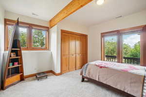 Carpeted bedroom with beamed ceiling and a closet