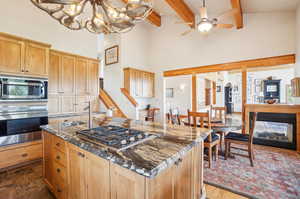 Kitchen with beamed ceiling, dark stone counters, a center island with sink, and stainless steel appliances