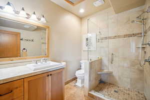 Bathroom with tile patterned floors, toilet, vanity, and an enclosed shower