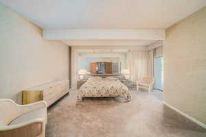 Bedroom featuring a textured ceiling and light colored carpet