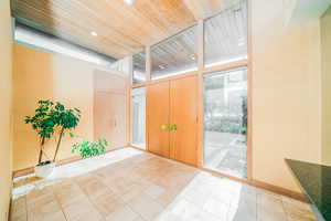 Tiled foyer with a wall of windows and wooden ceiling