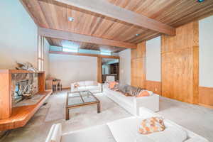 Carpeted living room featuring a fireplace, beamed ceiling, and wood ceiling