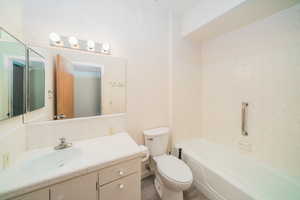 Full bathroom featuring vanity, tiled shower / bath combo, and toilet