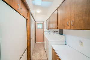 Washroom featuring light tile patterned floors, separate washer and dryer, and cabinets