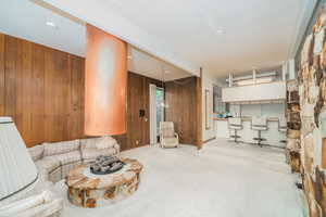 Carpeted living room featuring a textured ceiling and wooden walls