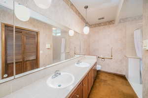 Bathroom featuring toilet and dual bowl vanity