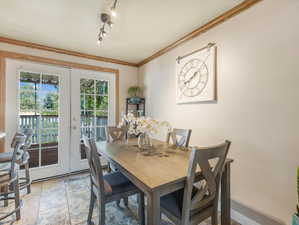 Tiled dining area with french doors, crown molding, and rail lighting