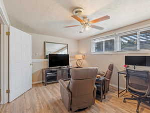 Office area with a textured ceiling, ceiling fan, and light wood-type flooring