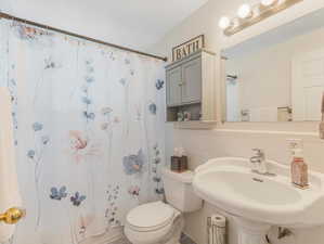 Bathroom featuring sink, toilet, backsplash, and tile walls