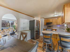 Kitchen with a breakfast bar, light tile patterned floors, kitchen peninsula, appliances with stainless steel finishes, and sink