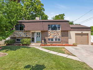 View of front of property with a garage and a front lawn