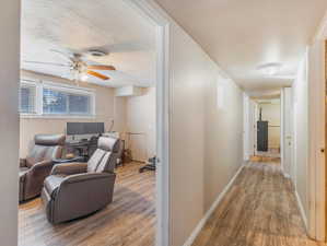 Hall with a textured ceiling and hardwood / wood-style flooring