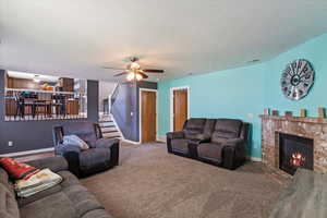 Living room featuring carpet floors, a fireplace, and ceiling fan