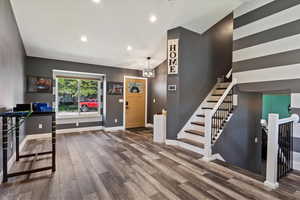 Foyer entrance with hardwood / wood-style floors and an inviting chandelier