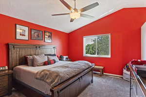 Carpeted bedroom with lofted ceiling, a textured ceiling, and ceiling fan