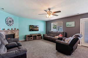 Living room featuring carpet flooring, a textured ceiling, and ceiling fan