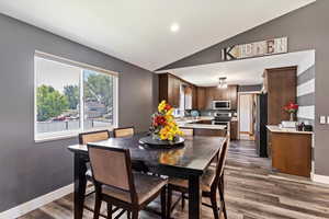 Dining area with dark hardwood / wood-style floors, lofted ceiling, and sink