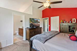 Bedroom with light tile patterned floors, lofted ceiling, ensuite bath, and ceiling fan