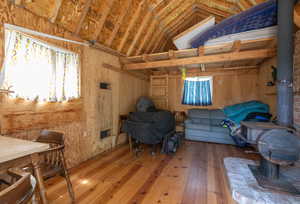 Interior space with wood-type flooring, vaulted ceiling, and a wood stove