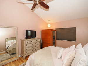 Bedroom with ceiling fan, lofted ceiling, and light hardwood / wood-style floors