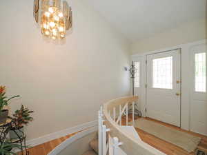 Foyer with wood-type flooring, lofted ceiling, and a chandelier