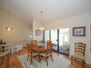 Dining space featuring an inviting chandelier, light wood-type flooring, and vaulted ceiling