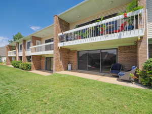 Rear view of house with a balcony, a patio, and a lawn