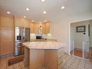 Kitchen featuring a center island, light hardwood / wood-style flooring, tile counters, and stainless steel refrigerator with ice dispenser