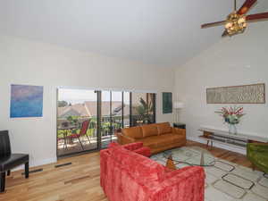 Living room with ceiling fan, light hardwood / wood-style flooring, and high vaulted ceiling