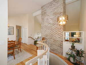 Corridor with beamed ceiling, a notable chandelier, light hardwood / wood-style flooring, and high vaulted ceiling