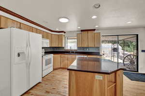 Kitchen with a kitchen island, sink, white appliances, and light hardwood / wood-style floors