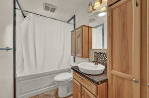 Full bathroom with vanity, shower / bath combo with shower curtain, toilet, tile patterned flooring, and backsplash