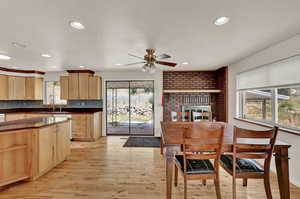 Kitchen featuring brick wall, ceiling fan, backsplash, and light hardwood / wood-style floors