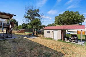 View of yard featuring a trampoline, a storage unit, and an outdoor fire pit