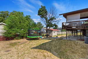 View of yard with a deck, a patio area, a shed, and a trampoline