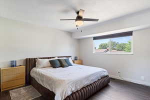 Bedroom with a textured ceiling, wood-type flooring, and ceiling fan