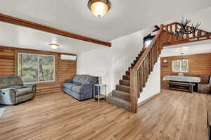 Living room with light wood-type flooring, wooden walls, a chandelier, and a textured ceiling