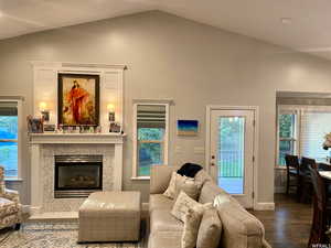 Living room featuring vaulted ceiling, a tile fireplace, and hardwood / wood-style floors