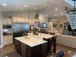 Kitchen with dark hardwood / wood-style flooring, a large island, ceiling fan, built in appliances, and sink