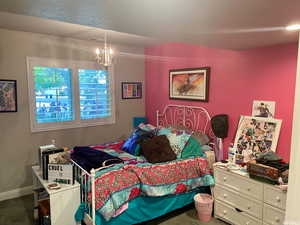 Carpeted bedroom featuring a notable chandelier