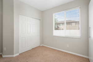 Unfurnished bedroom featuring light carpet and a closet