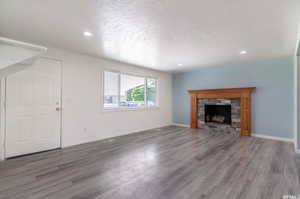 Unfurnished living room featuring a textured ceiling, a fireplace, and hardwood / wood-style flooring