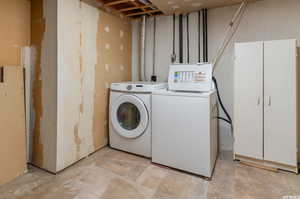 Laundry room with washing machine and dryer and light tile patterned floors