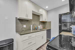 Kitchen featuring hardwood / wood-style flooring, dishwasher, tasteful backsplash, and sink